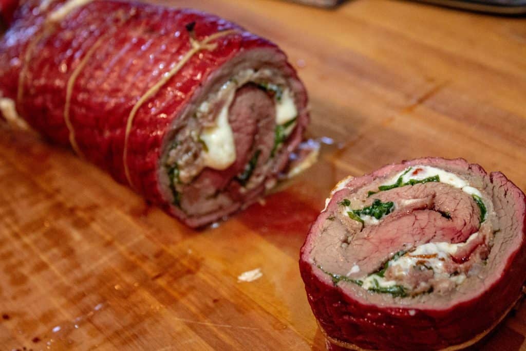 Flank Steak Pinwheels starting to be sliced on a cutting board