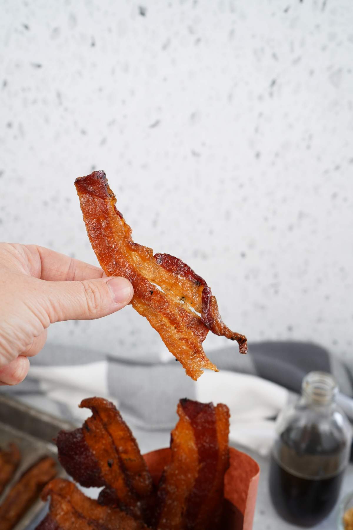 Slice of candied bacon in hand.