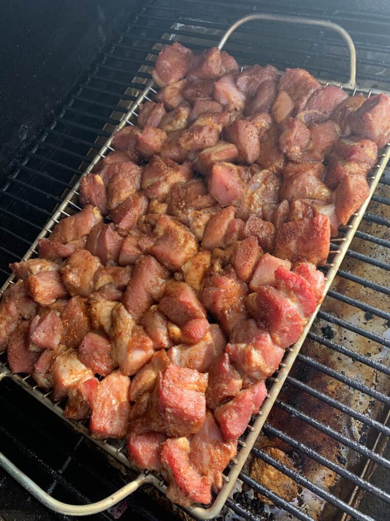 Chunks of pork shoulder on a grilling rack in a smoker
