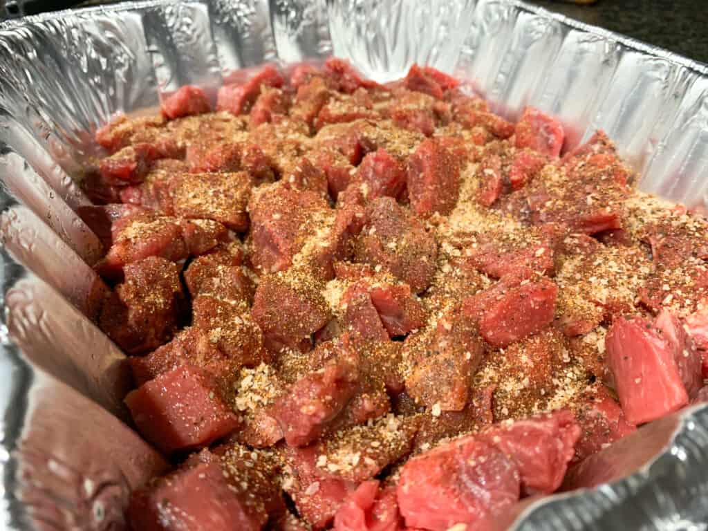 aluminum pan filled with stew meat tossed in bbq rub