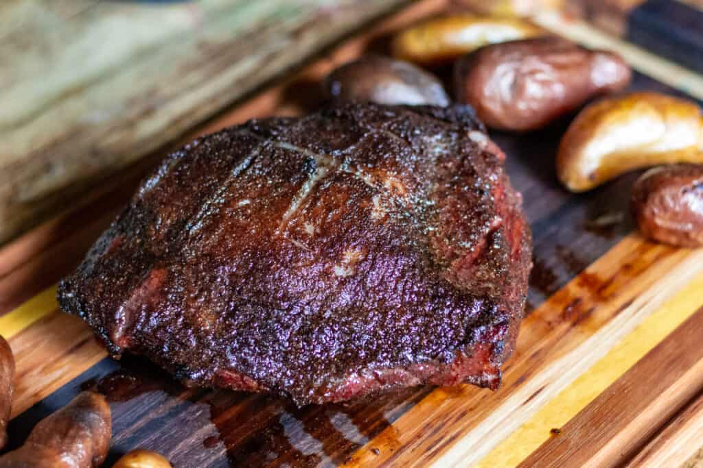smoked picanha steak with potatoes on a cutting board