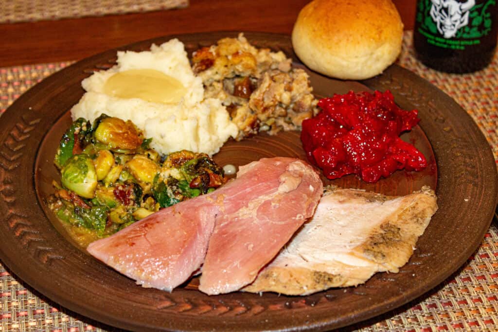 smoked turkey slices on a plate with traditional sides - how to smoke a turkey