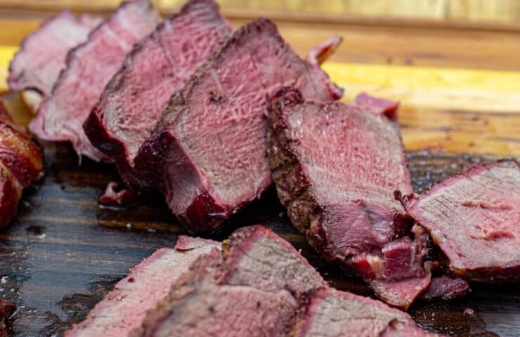 smoked filet mignon wrapped in bacon sliced on a cutting board