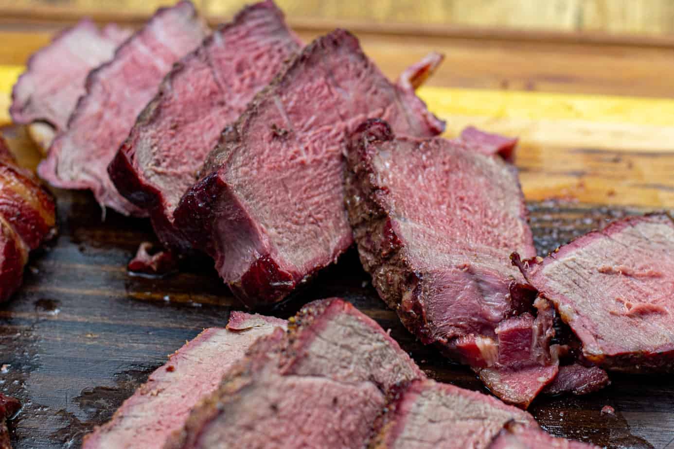 smoked filet mignon wrapped in bacon sliced on a cutting board