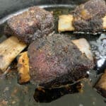 beef short ribs in a cast iron skillet on the smoker