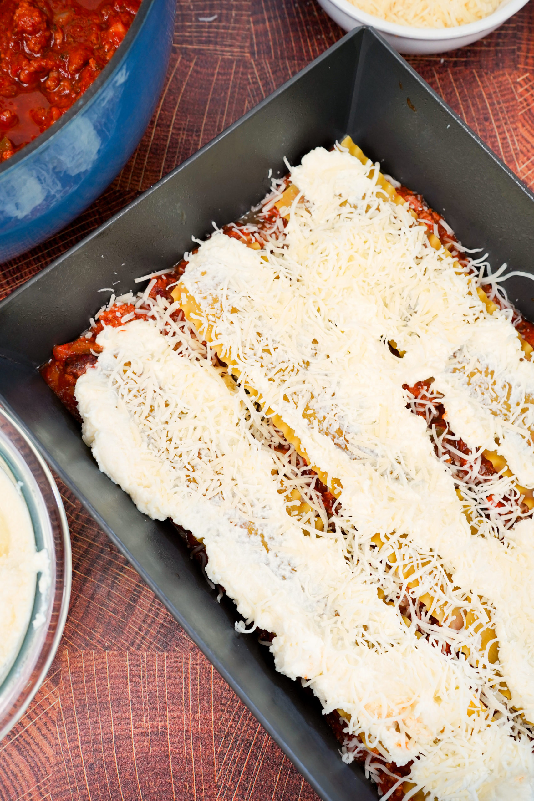 Layers of lasagna, sauce, and cheese in baking dish. 