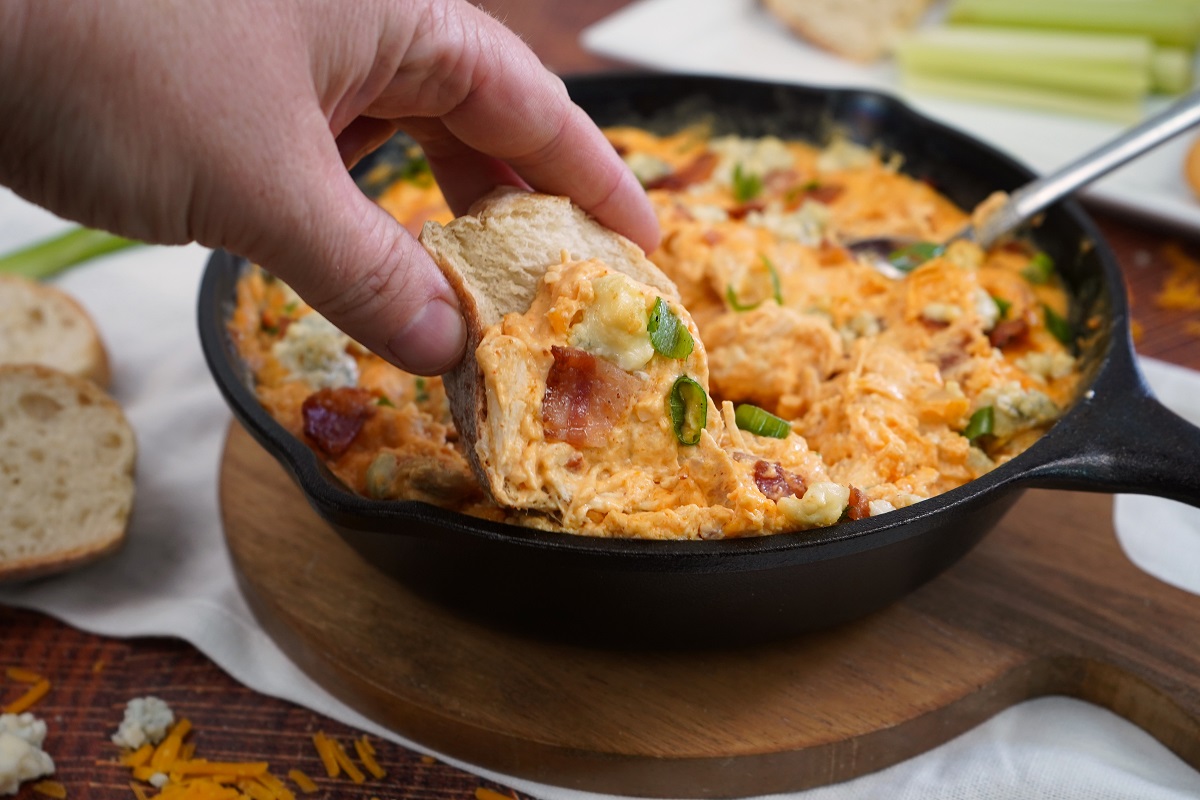 Bread being dipped into buffalo chicken dip.