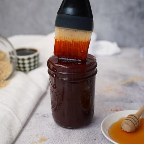 Sweet and spicy bbq sauce in mason jar with brush