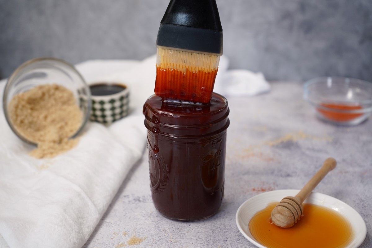 Sweet and spicy bbq sauce in mason jar with brush